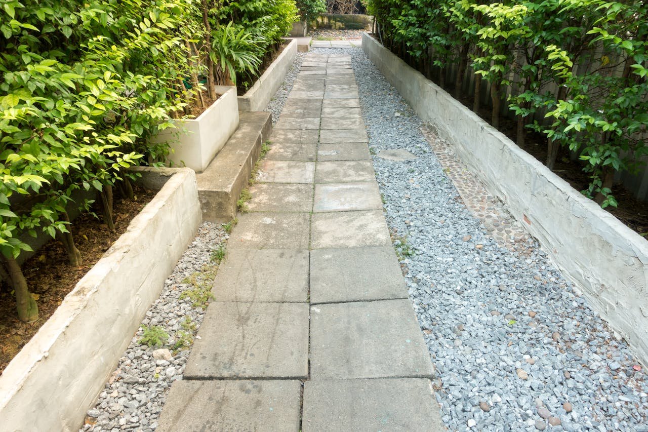 Services A tranquil garden path surrounded by lush green plants and a pebbled walkway.