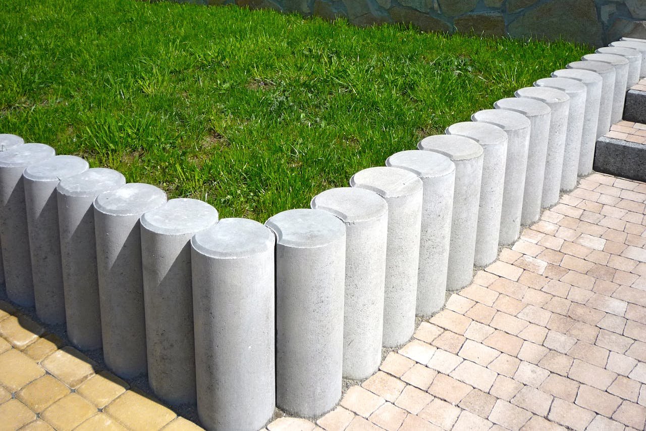 Services Cylindrical concrete blocks form a stylish lawn boundary, enhancing garden aesthetics.